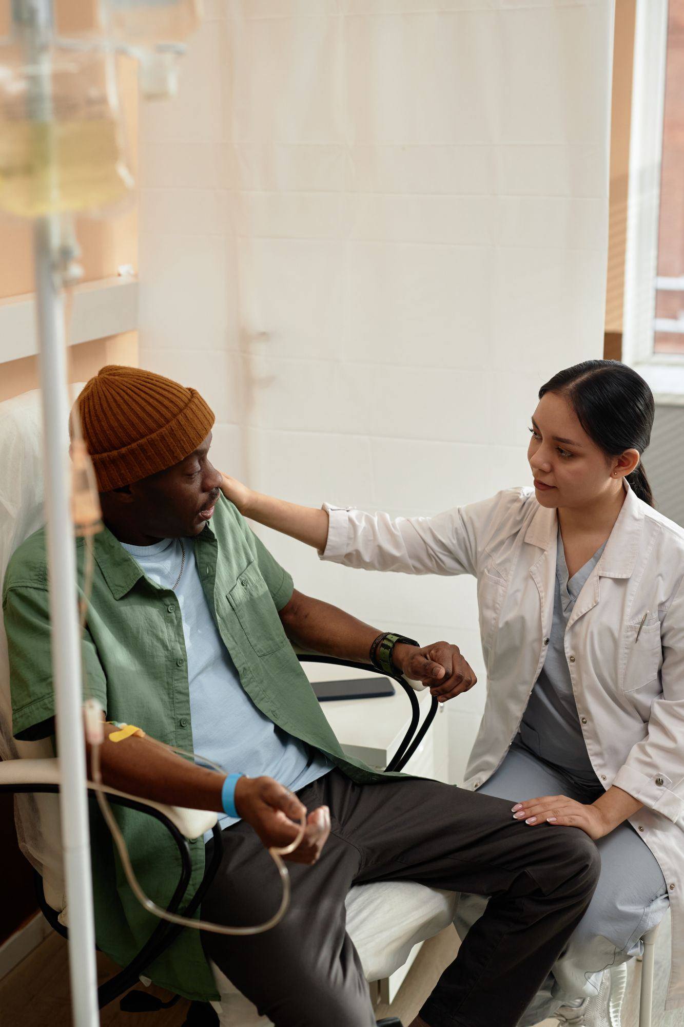 Patient receiving IV drip therapy with a nurse at bedside