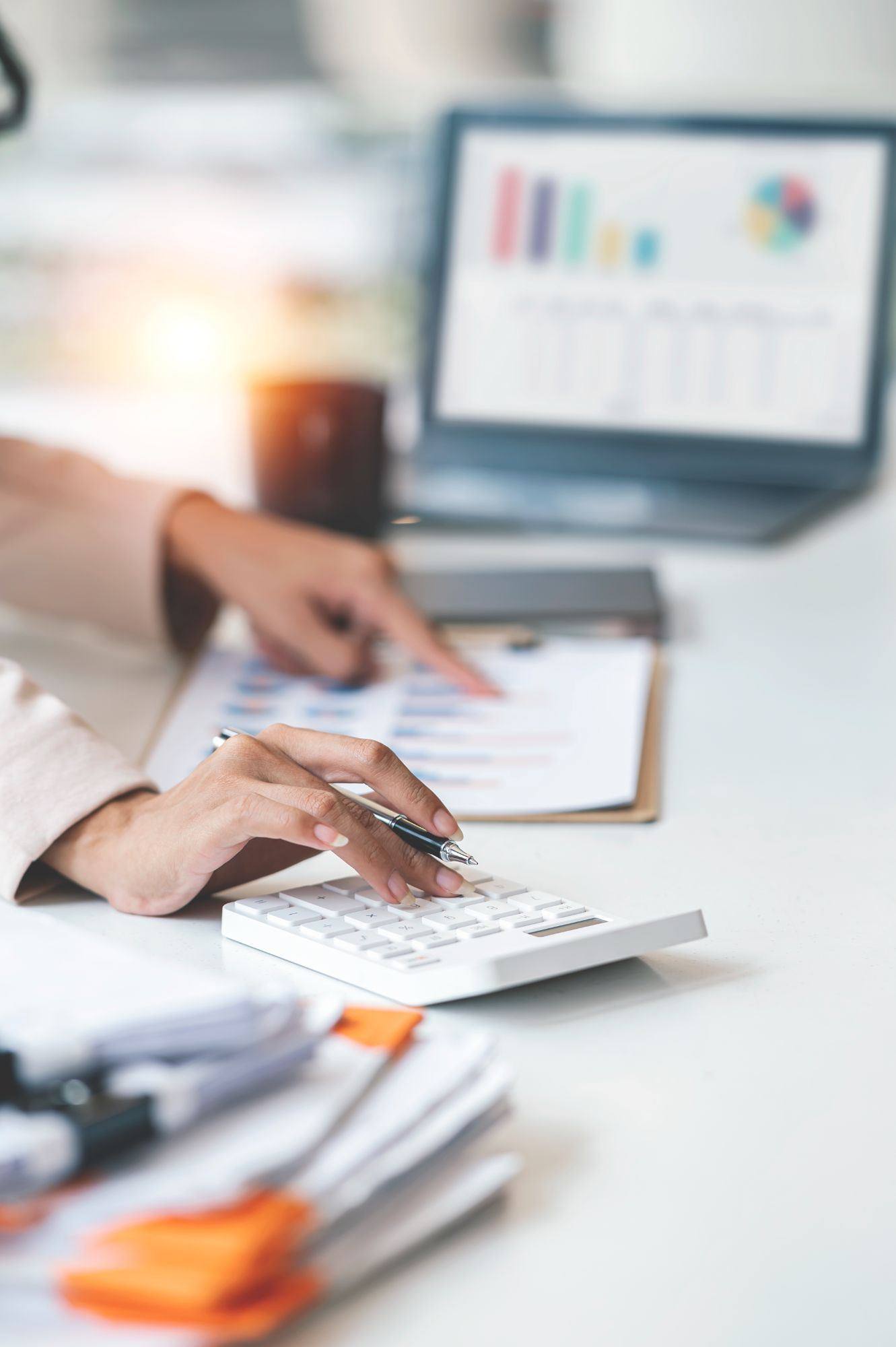 Processing payroll figures with a calculator and laptop